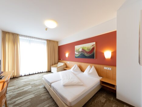 Bright double room with two beds and a television. | © Harry Schiffer