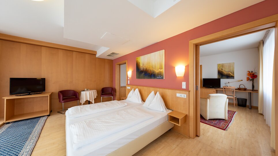 Modernes Doppelzimmer mit zwei Betten, Fernseher und Sitzecke. | © Harry Schiffer