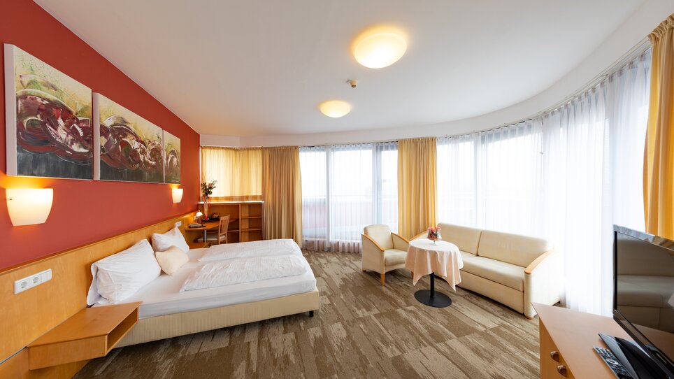 Doppelzimmer mit großen Fenstern, bequemen Möbeln und moderner Einrichtung. | © Harry Schiffer