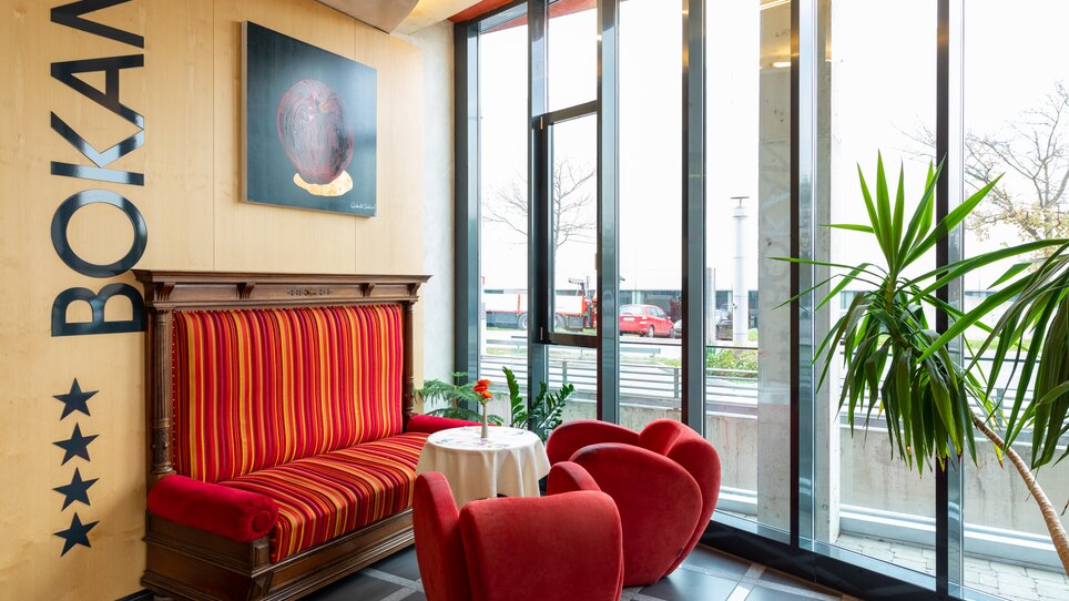 Moderne Sitzecke im Hotel Bokan mit rotem Sofa und Kunstwerk. | © Harry Schiffer