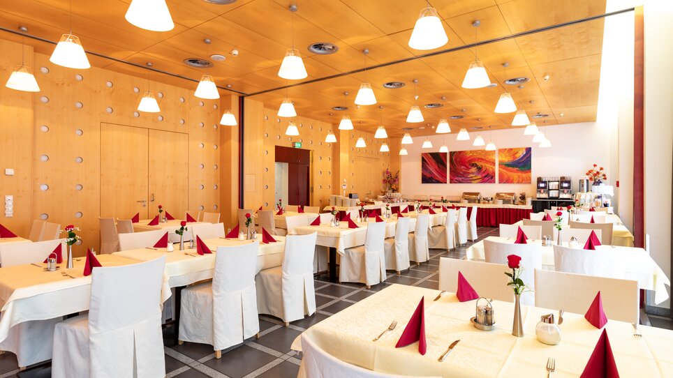 Restaurant mit Tischen und Stühlen, dekoriert mit roten Servietten und Rosen. | © Harry Schiffer