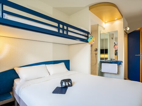 Cozy hotel room featuring a double bed and an elevated bed. | © Ibis Budget