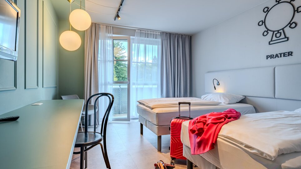 Ein einfaches Zimmer im Hotel Ibis Styles Graz Messe mit zwei Betten und Balkon. | © Katharina Haag