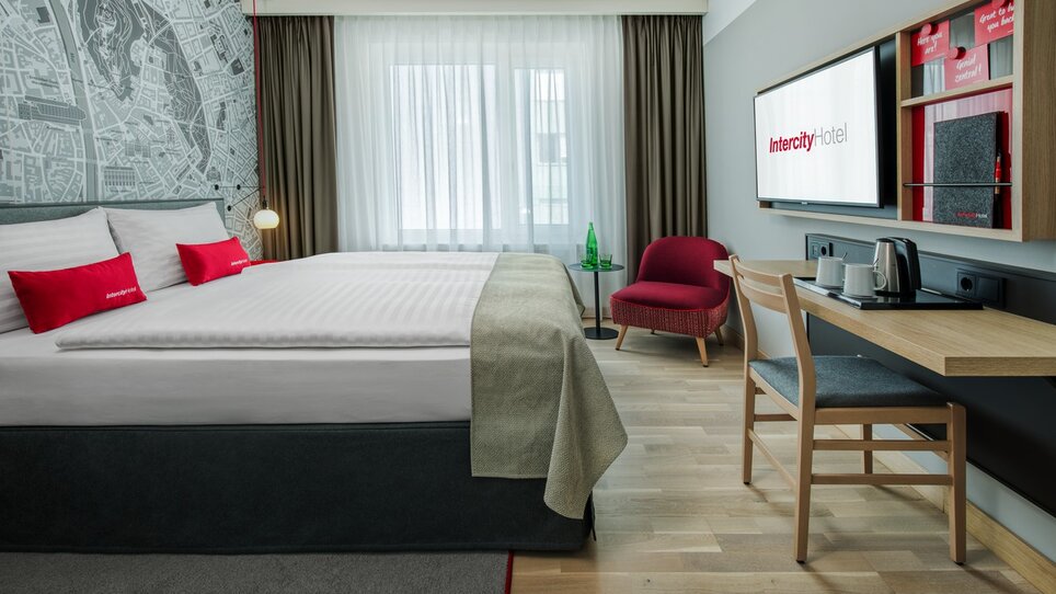 Ein modernes Hotelzimmer mit Doppelbett, Schreibtisch und Fernseher im IntercityHotel Graz. | © ICHG
