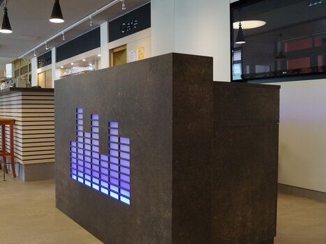 Modern reception counter with illuminated equalizer design. | © JUFA Hotel Graz City