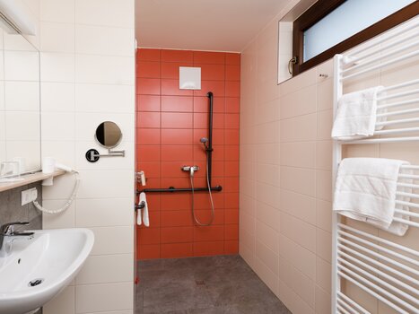 Helles Badezimmer mit Duschbereich und Waschbecken. | © Jufa Hotels