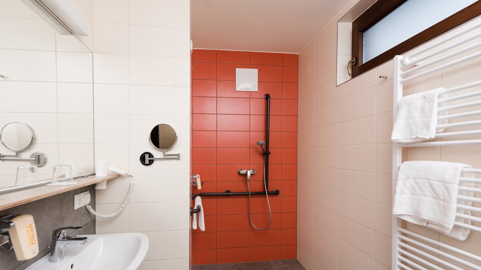 Helles Badezimmer mit Duschbereich und Waschbecken. | © Jufa Hotels