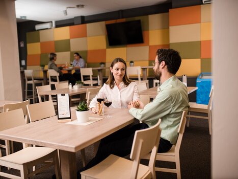 Ein Paar beim Abendessen in einem Restaurant mit Weingläsern und Pflanzen. | © Jufa Hotels