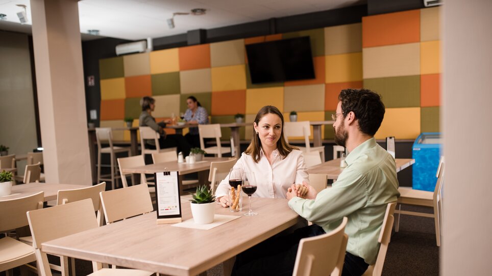 Ein Paar beim Abendessen in einem Restaurant mit Weingläsern und Pflanzen. | © Jufa Hotels