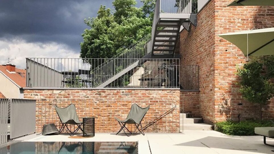 Hotel KAI 36 mit Pool und Treppe, umgeben von Bäumen. | © KAI 36