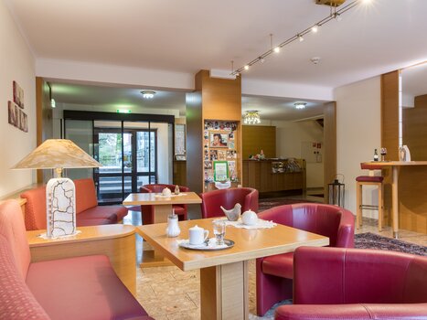 Un'area caffè accogliente con sedute rosse e tavoli. | © Mario Gimpl
