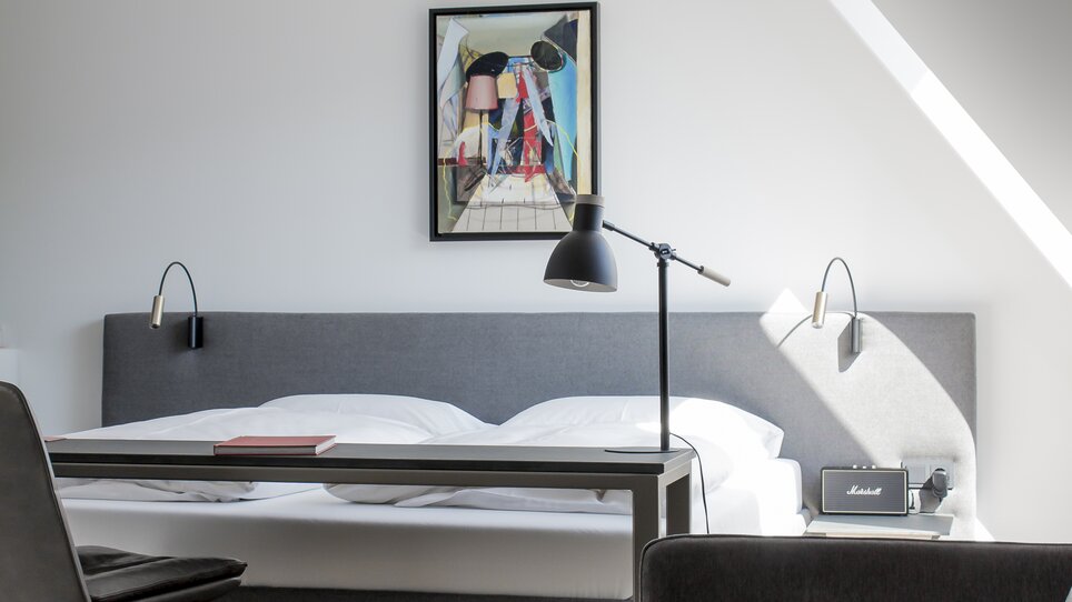 Modernes Doppelzimmer mit Kunstwerk, Bett und Leselampe. | © Lendhotel