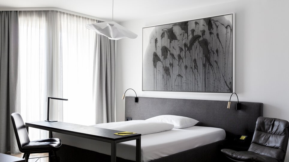 Ein stilvolles Doppelzimmer mit minimalistischer Einrichtung, einem großen Bett und einem Schreibtisch. | © Lendhotel