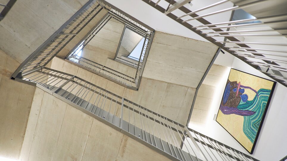 Ein modernes Treppenhaus mit einem Kunstwerk an der Wand. | © Lendhotel