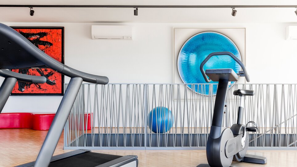 Moderne Fitnessgeräte in einem stilvollen Raum mit Kunstwerken. | © Lendhotel
