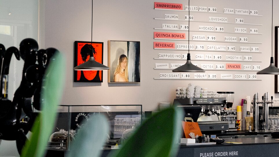 Ein modernes Café mit Kunstwerken und einer Snackbar. | © Lendhotel