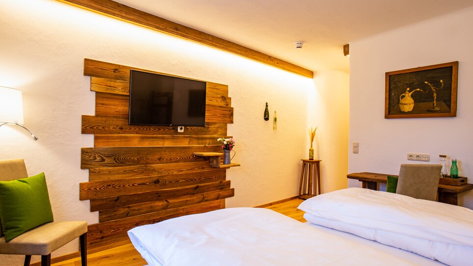 Zimmer mit Doppelbett, Holzwand und TV. | © Lendplatzl GmbH