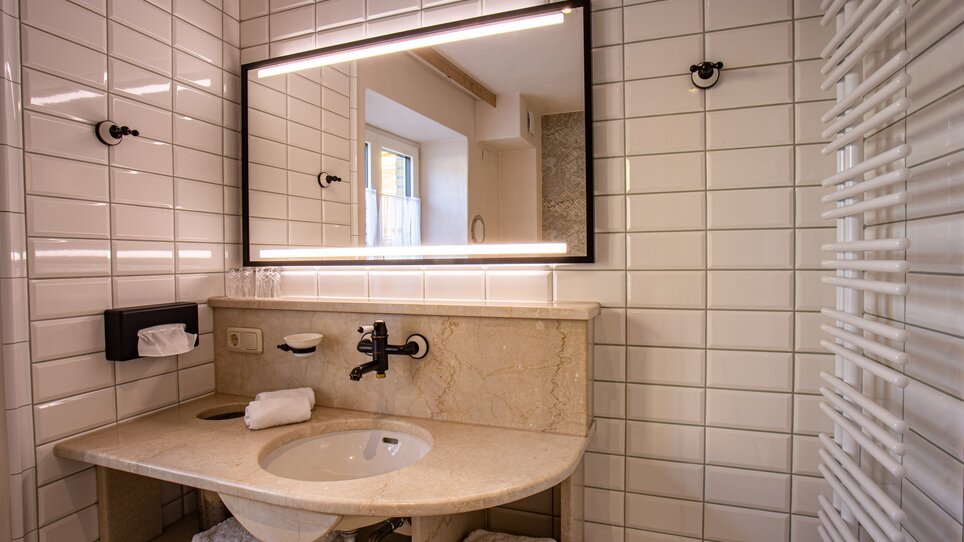 Ein modernes Badezimmer mit Waschbecken, Spiegel und Handtüchern. | © Lendplatzl GmbH