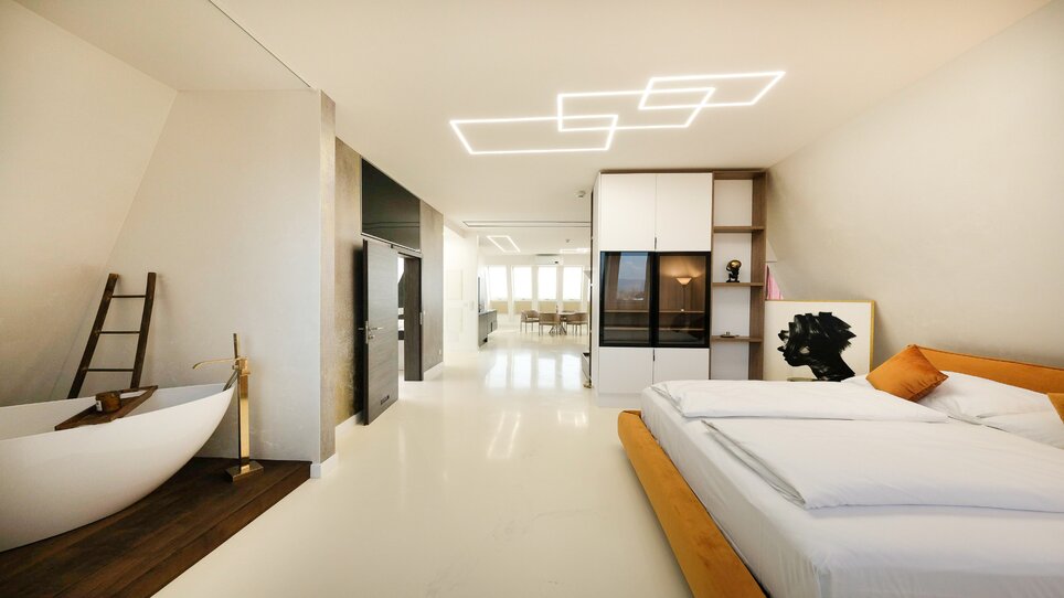 Helles Doppelzimmer mit großem Bett und freistehender Badewanne. | © NED Hotel