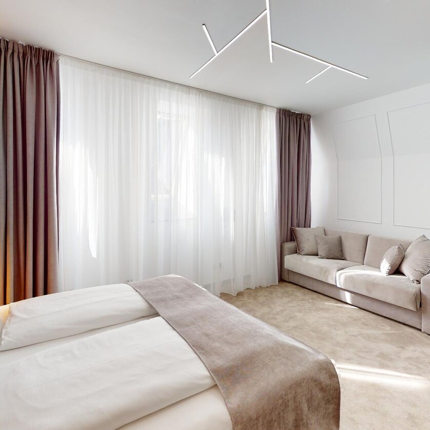 NED Hotel - Zimmer Superior | © NED Hotel Modernes Doppelzimmer mit hellen Vorhängen und gemütlichem Sofa. | © NED Hotel