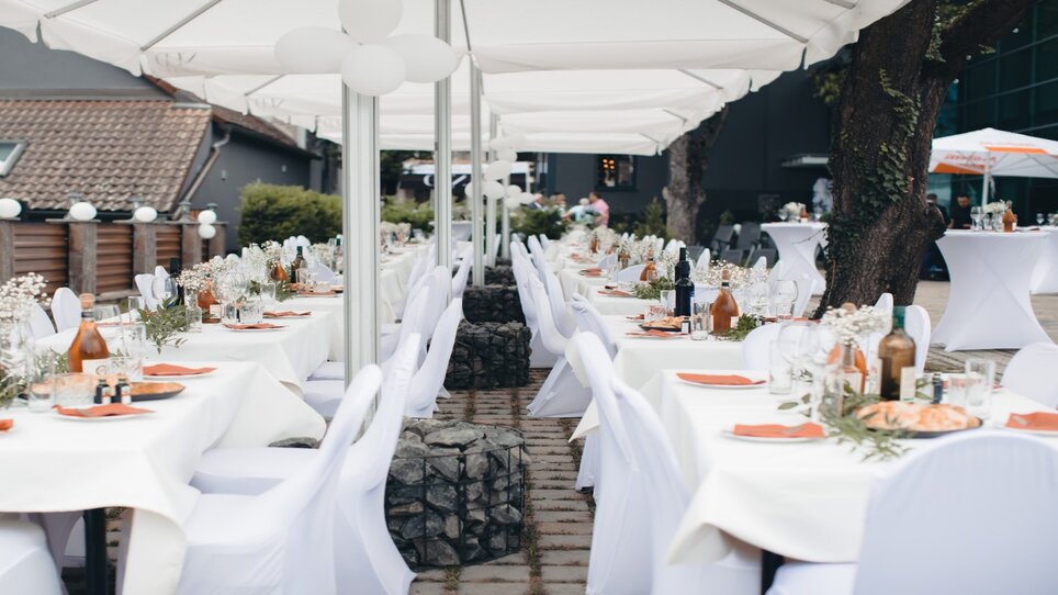 Festlich gedeckte Tische im Freien, dekoriert mit Blumen und Geschirr. | © NED Hotel