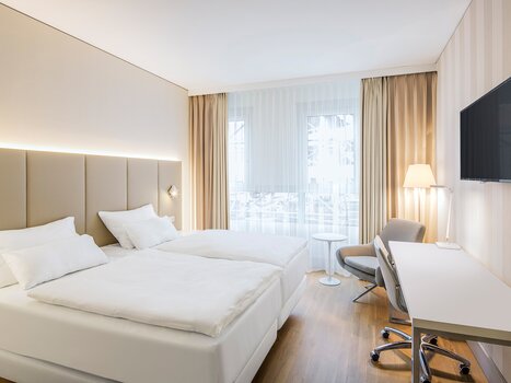 Camera doppia moderna con due letti e scrivania. | © NH Hotel