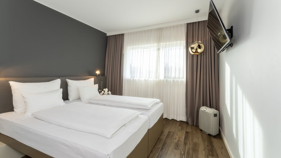 Modernes Zimmer mit Doppelbett und Fernseher. | © Plaza INN Graz
