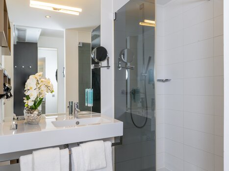 Bright bathroom with shower, sink, and towels. | © Plaza INN Graz