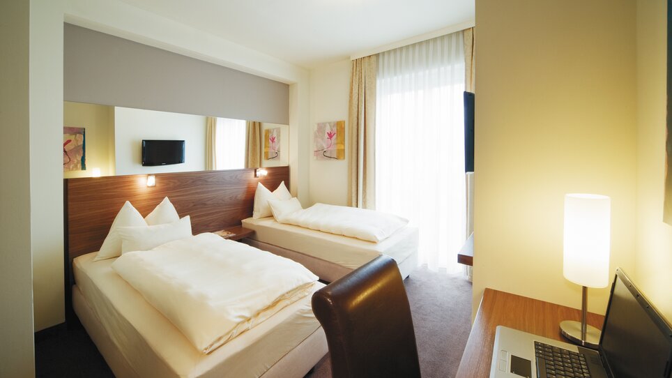 Helles Doppelzimmer mit zwei Betten und Schreibtisch. | © Roemerstube