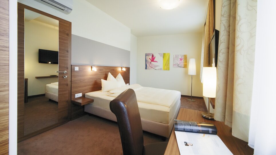 Helles Doppelzimmer mit großen Bett und Fernseher. | © Roemerstube 