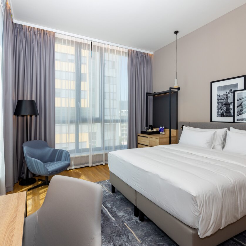 Camera doppia moderna con letto grande e sedia. | © Graz Tourismus - Harry Schiffer