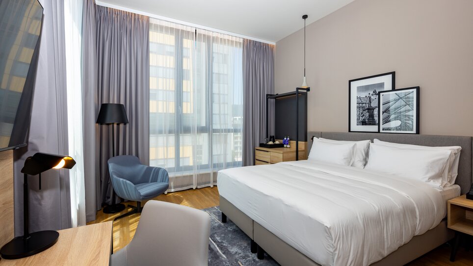 Modern double room with large bed and chair. | © Graz Tourismus - Harry Schiffer