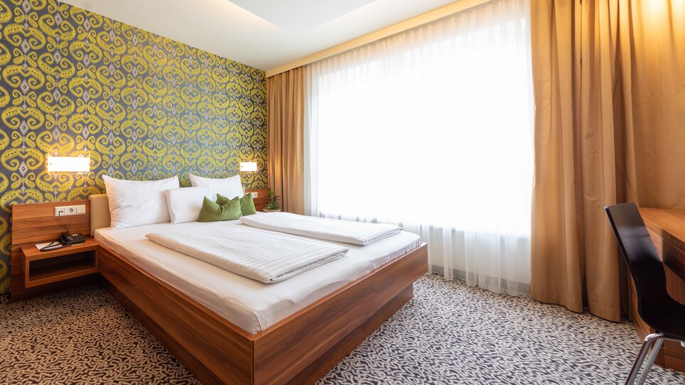 Helles Doppelzimmer mit großem Bett und Fenster. | © Hotel Süd Art