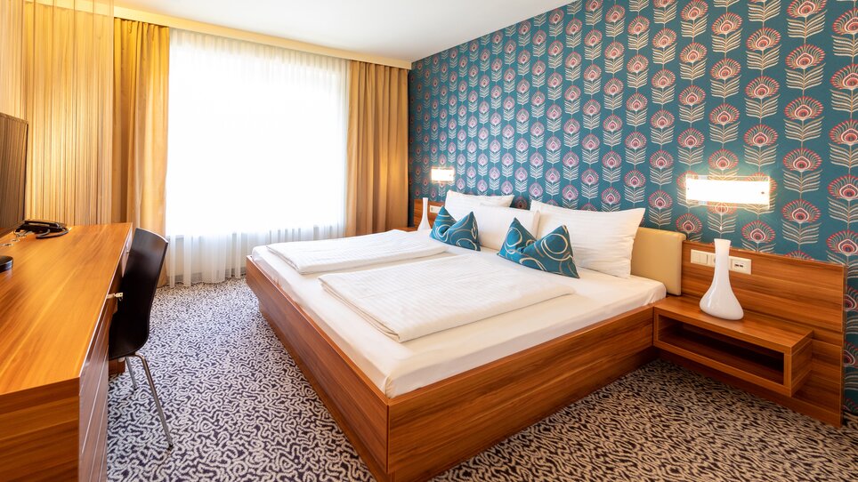 Modernes Zimmer mit einem Doppelbett und dekorativen Kissen. | © Hotel Süd Art