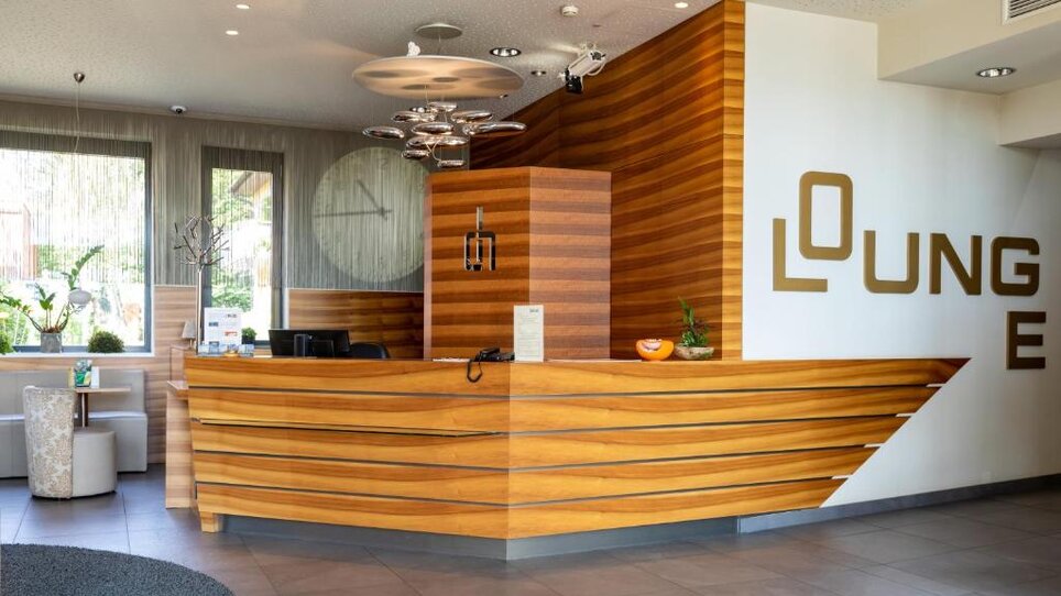 Moderne Hotelrezeption mit Holzoberflächen und Sitzgelegenheiten. | © Hotel Süd Art 