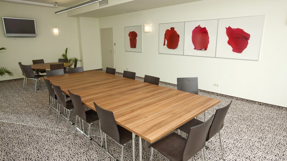 Konferenzraum mit langer Tafel und Kunstwerken an der Wand. | © Hotel Süd Art
