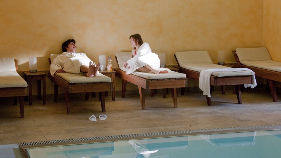 Ein Paar entspannt in einem Spa mit Liegen und einem Pool. | © Hotel Süd Art 