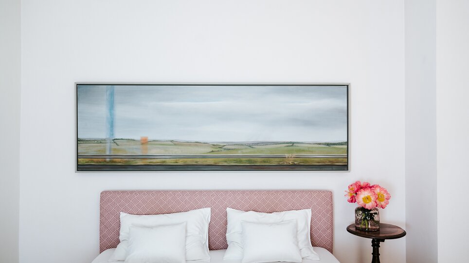 Suite im Schlossberghotel in Graz mit einem großen Betten und einer Landschaftsmalerei. | © Lupi Spuma