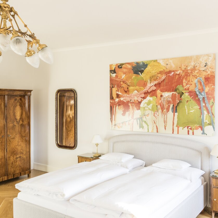 Bright double room with a large bed and abstract artwork. | © Schlossberghotel