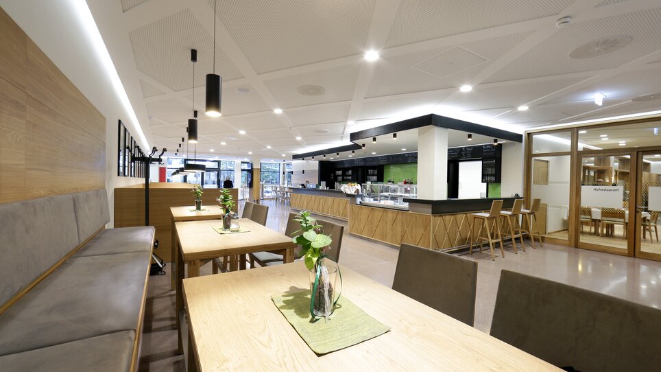 Interior view of a café with wooden tables and plants. | © Foto Pachernegg