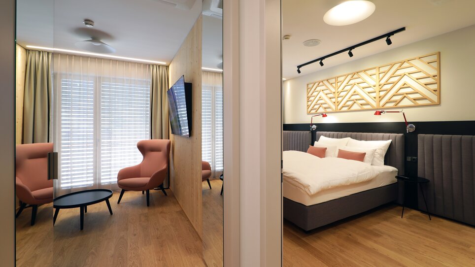 Panoramica di una camera d'hotel con area soggiorno e letto. | © Hotel Steiermarkhof