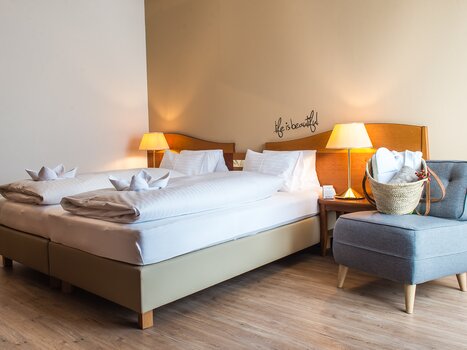 Bright room with double bed and cozy armchair. | © Hotel Stoiser