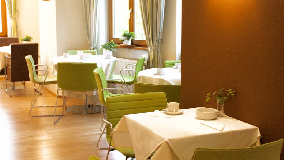 A modern restaurant area with green chairs and tablecloths. | © Rueckert