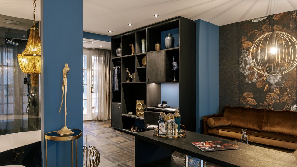 Area soggiorno stilosa con pareti blu e mobili moderni in Aiola Living. | © Aiola Living