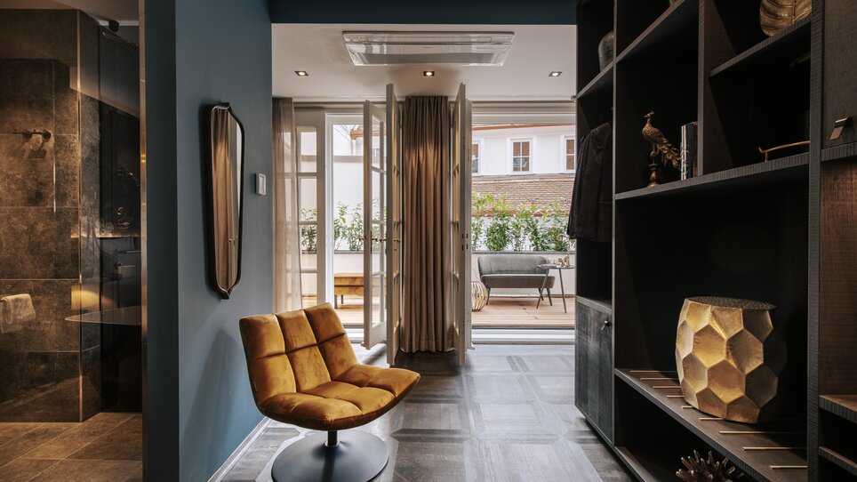 Un corridoio elegante con una sedia arancione e un balcone. | © Aiola Living