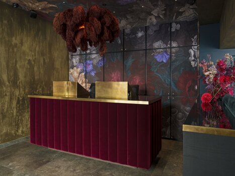 Receptione moderna con velluto rosso, accenti dorati e motivi floreali. | © Aiola Living