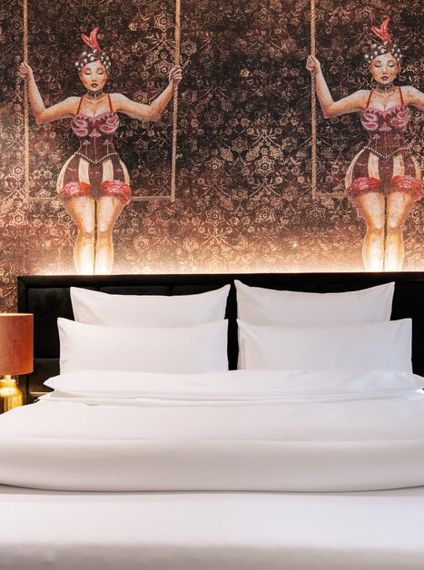 Elegantes Schlafzimmer mit künstlerischem Wanddesign und modernem Mobiliar. | © Aiola Living