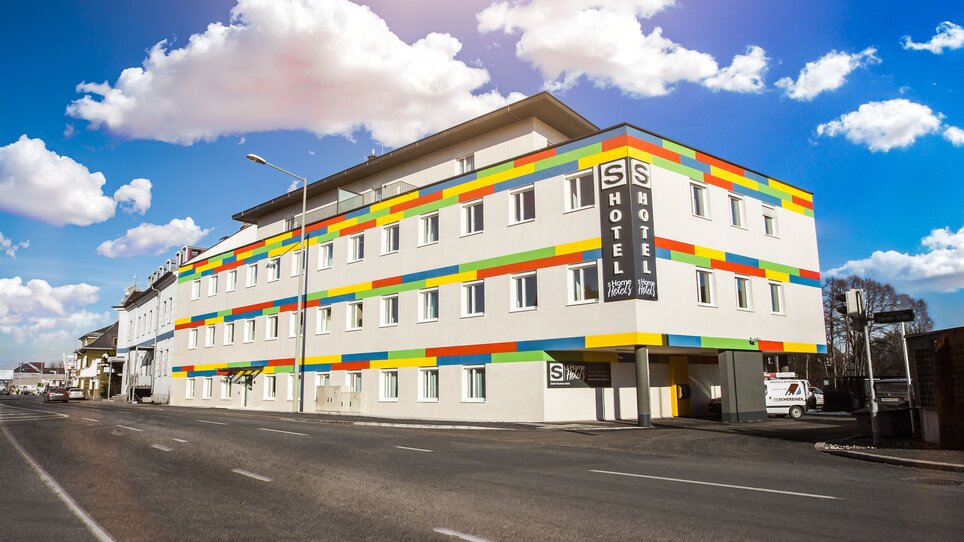 Luminoso edificio alberghiero con strisce colorate e finestre. | © sHome Hotel
