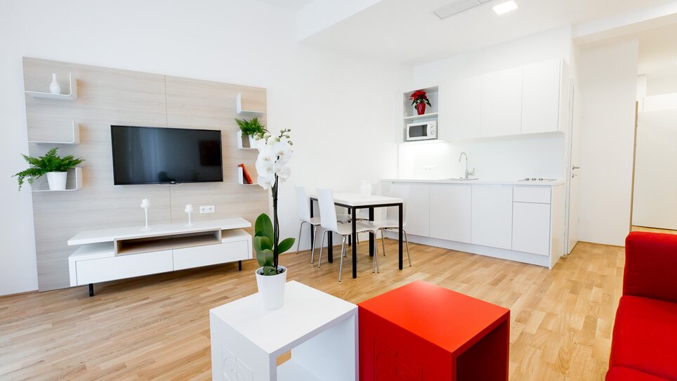 Cucina abitabile luminosa e moderna con TV e tavolo da pranzo. | © sHome Hotel