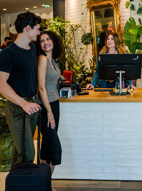 Check-in presso l'Hotel Weitzer di Graz | © Graz Tourismus - Mias Photoart Una coppia si trova davanti alla reception dell'Hotel Weitzer con una valigia, per effettuare il check-in. | © Graz Tourismus - Mias Photoart